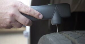 Técnico medindo a profundidade dos sulcos de um pneu de carga durante a inspeção da carcaça